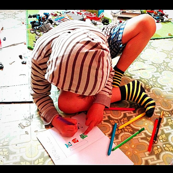 HIGH ANGLE VIEW OF A BOY SITTING ON THE FLOOR