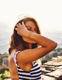 Portrait of smiling young woman standing against sky