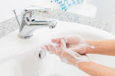 Midsection of woman washing hands at sink