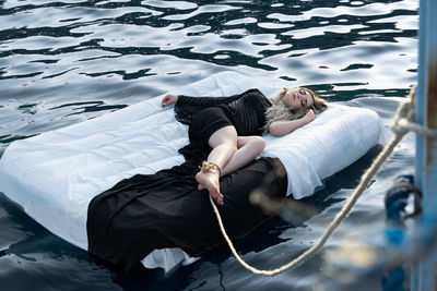 High angle view of woman sleeping on pool raft in lake