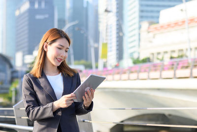 Young woman using phone while standing in city