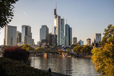 River by buildings in city against sky