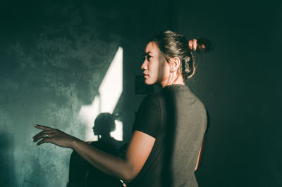 Side view of young woman standing against gray background