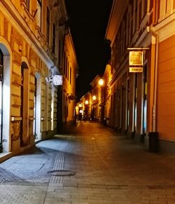 Illuminated street amidst buildings at night