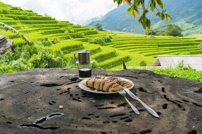 Pancakes and coffee with countryside views of sunlit green rice terraces on the background