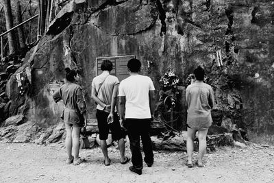 Rear view of friends looking at information sign on weathered wall