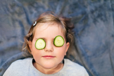 High angle view of woman with cucumber on eyes