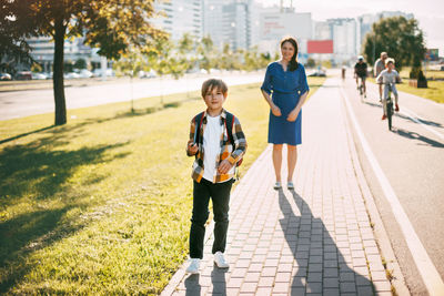 A mother walks her son to school. mom waits until the boy reaches the school gates.