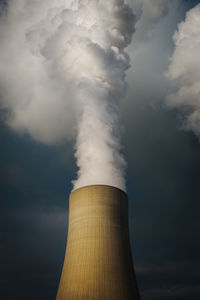 Low angle view of smoke stacks against sky