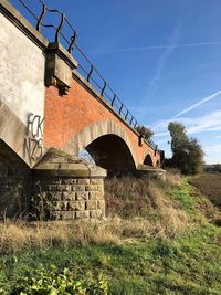 Low angle view of arch bridge on field against sky