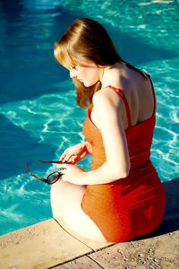 Young woman sitting by swimming pool