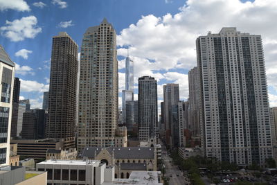 Low angle view of modern buildings against cloudy sky