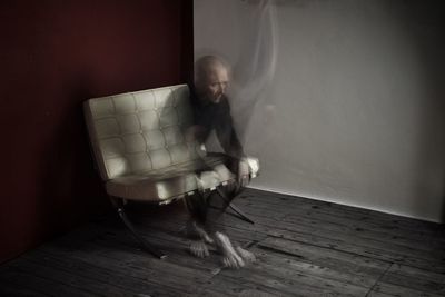 Blurred motion of man sitting on chair at home