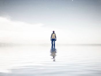 Man standing in sea against sky