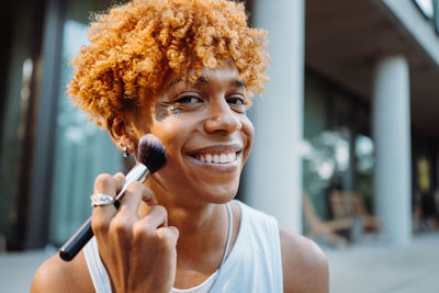 African american visagist holding brush and preparing makeup
