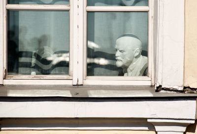 Reflection of statue on glass window of building