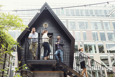 Low angle view of business people discussing on log cabin at office yard