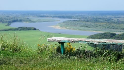 Close up view on aged wooden bench by panoramic landscape of river valley