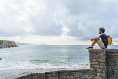 Rear view of man standing at beach against sky