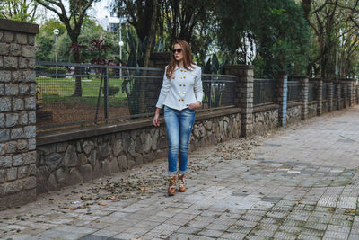 Full length portrait of woman standing on footpath