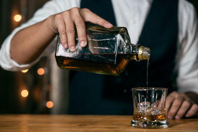 Midsection of man pouring wine in glass on table