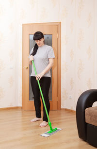 Woman moping hardwood floor at home