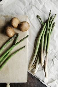 Top view of arranged fresh stems of asparagus on paper and mushrooms