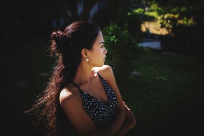 Young woman looking away while standing against blurred background
