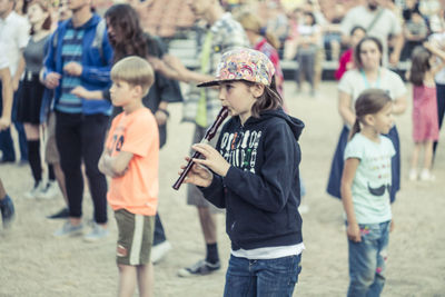 Girl playing flute while standing against crowd