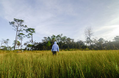 Rear view of man standing in farm against sky