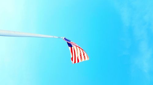 Low angle view of flag against clear blue sky