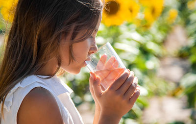 Cute girl drinking water at sunflower field