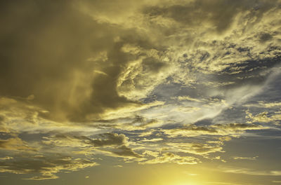 Low angle view of sunlight streaming through clouds