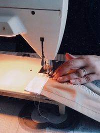 Cropped hand of woman sewing textile on machine