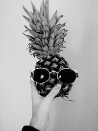 Close-up of hand wearing sunglasses against white background