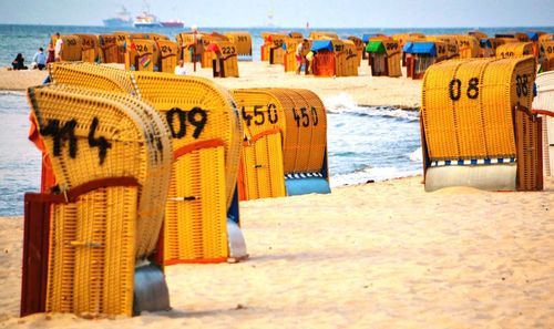 Close-up of deck chairs on beach against sky