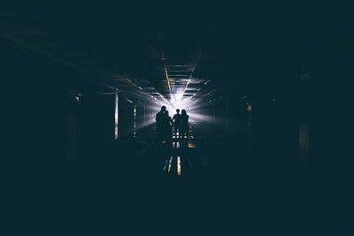 Silhouette people standing in illuminated tunnel