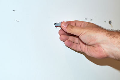 Close-up of hand holding ring against white background