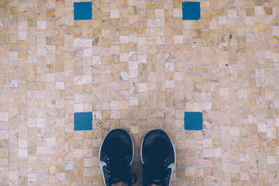 Low section of person standing on brick wall