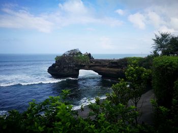 Rock formation by sea against sky