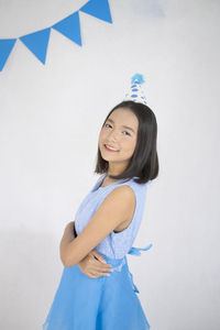 Portrait of a smiling young woman standing against wall