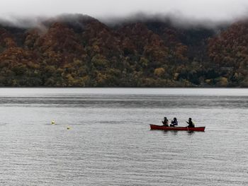 People in boat on river against trees