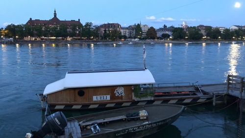 Boats moored in river with city in background