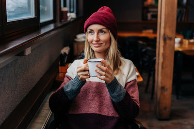 Apres ski, a woman in a coffee sitting in a cozy bar drinks coffee.