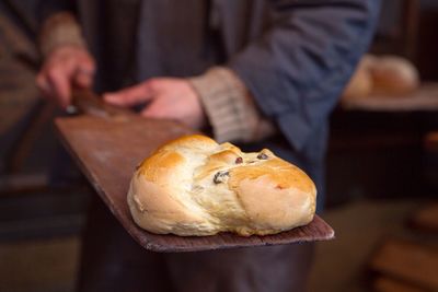 Close-up of bread on serving board being held by man