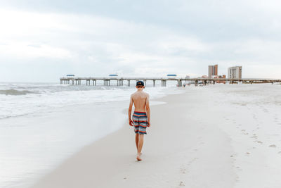 Rear view of teenage boy walking on beach