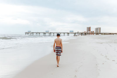 Rear view of man walking on beach