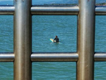 Man feeding bird on railing by sea