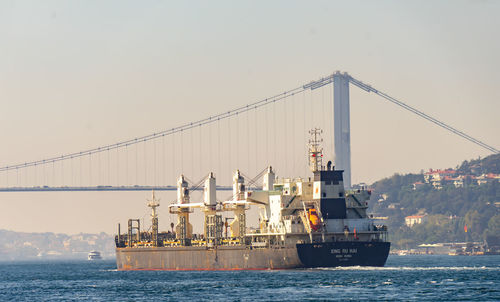 Ship on bridge over sea against sky