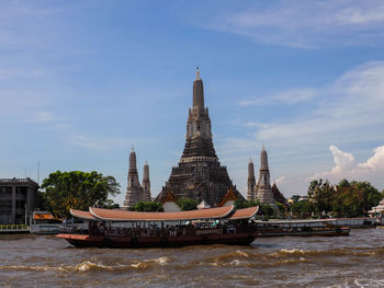 Boats in river by building against sky